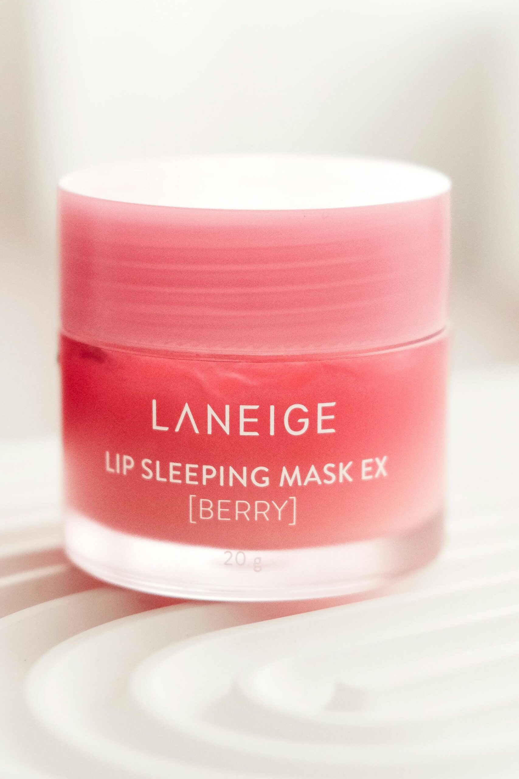 Close-up of Laneige Lip Sleeping Mask EX in berry flavor on textured surface. Product photography.